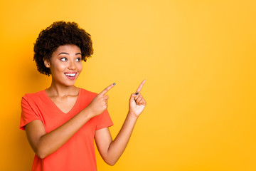 Copyspace photo of attractive nice cute charming fascinating excited girlfriend black pointing at emptiness wearing t-shirt smiling toothily isolated over yellow vivid color background