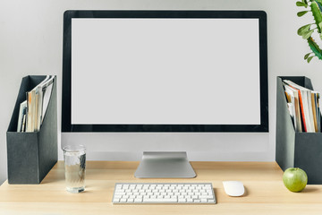 Computer monitor with mockup white screen on office table with supplies