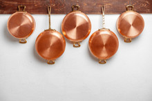 Row Of Shiny Clean Copper Pans, Different Size, Hung On Wooden Plank