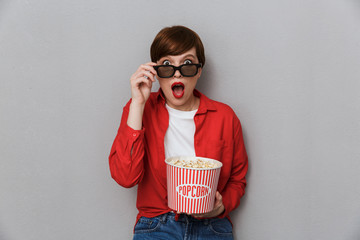 Poster - Image of shocked woman wearing 3D glasses holding bucket with popcorn