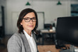 © mavoimages - Smiling businesswoman sitting at her desk in an office