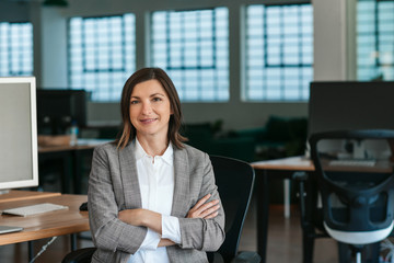 Smiling businesswoman sitting at her office desk in the afternoon