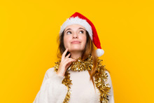 Girl With Christmas Hat Over Isolated Yellow Background Thinking An Idea