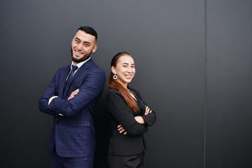 Businessman and businesswoman realtors on black office wall background, Asian Kazakh entrepreneurs