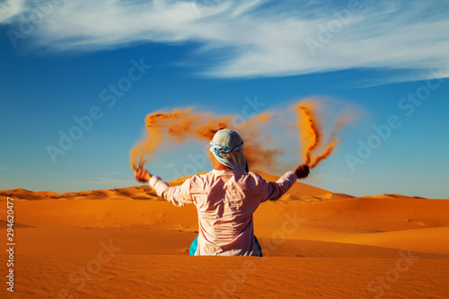 Fotografía Single Man throws sand in the Sahara desert at sunset.