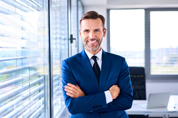 portrait of successful businessman standing in corner office