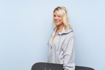 Young blonde woman over isolated background with skate