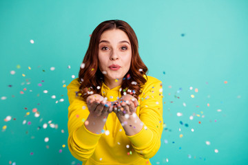 Wall Mural - Photo of charming cute fascinating nice young girlfriend blowing confetti at you to show her festive mood with emotional face expression isolated over turquoise vivid color background