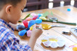 © Wutthichai - Asian boy painting a colourful plastic flower made from water bottle on wooden table outdoor.Recycled colorful plastic flowers.Recycle decoration.