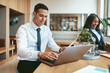 © Flamingo Images - Smiling businessman working on his laptop in a modern office
