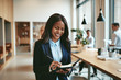 © Flamingo Images - Smiling African American businesswoman writing notes in a modern
