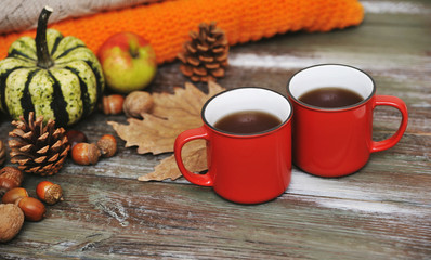 Autumn flat lay background. Pumpkins, apples, nuts,leaves, cups and sweater on wooden background.