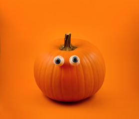 Halloween pumpkin with eyes stock images. Halloween pumpkin with eyes on a orange background. Cute halloween pumpkin with chocolate eyes. Single pumpkin isolated on orange background