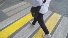 Top View Shot. Young Man No Face In A Blue Pants And White Sneakers With Leather Bag Crossing The City Road On Yellow White Crosswalk