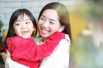 Wall Mural - Celebration concept. The girl and mother are enjoying Christmas. Cute girl gives his beloved mother a gift. New year's decorate in the living room.