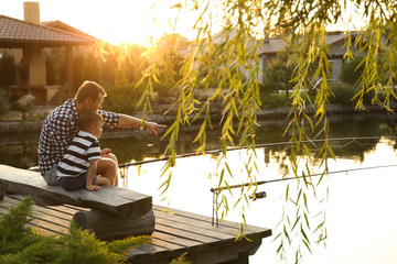 Dad and son fishing together on sunny day