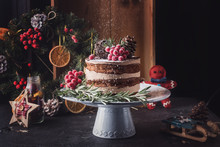 Rustic chocolate Christmas cake with citrus on a white dishes with green