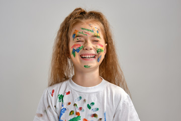 Wall Mural - Little girl in white t-shirt, with painted face is making grimaces while posing isolated on white. Art studio. Close-up.