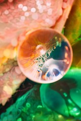 Surreal composition with glass ball coral sequin textile and holographic foil