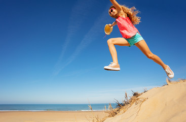 Wall Mural - Girl in long jump from sand dune on the sea beach