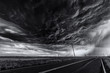 © Cavan Images - Heavy storm and cloud sky over road and farm fields, black and white
