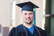 © Cavan Images - Smiling portrait of male graduate in black cap and gown