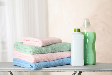 Wall Mural - Stack of clean towels and laundry liquid on ironing board, copy space