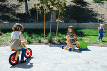 Two Little Girls Ride Wooden Push Bikes Outside