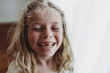 © Cavan Images - Portrait of young freckled smiling girl missing tooth with eyes closed