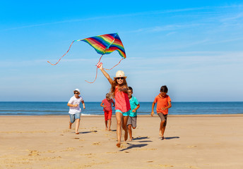 Canvas Print - Group of happy kids run with kite on the beach