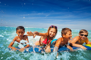 Group of happy kids boy and girls splash in sea