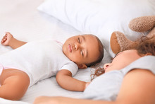 Young African-American Woman And Her Baby Sleeping On Bed