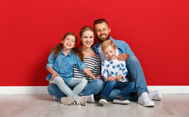 Wall Mural - happy family mother father and children daughter and son  near an   red wall