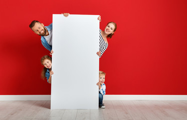 Wall Mural - happy family mother father and children daughter and son  near an   red wall with a white blank poster.