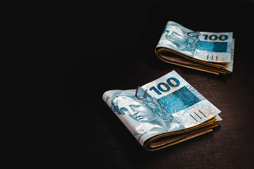 Wall Mural - Brazilian money pack on isolated black background. Money from Brazil, called REAL, together on a black table. Concept of financial value or withdrawal from FGTS, banking.