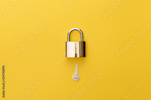Fotografía top view of padlock and key on yellow background