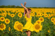 © Михаил Решетников - A red-haired woman in a yellow dress is standing in a field of sunflowers. Beautiful girl in a skirt sun enjoys a cloudless day in the countryside. Pink locks of hair.