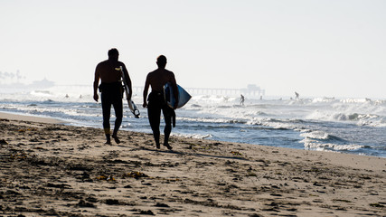 two surfers' silhouette with surfers in the background 