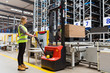 Storehouse employee in uniform working on forklift in modern automatic warehouse.Boxes are on the shelves of the warehouse. Warehousing, machinery concept. Logistics in stock.