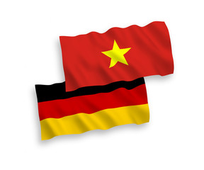 National vector fabric wave flags of Germany and Vietnam isolated on white background. 1 to 2 proportion.