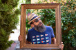 A hipster man posing inside of a picture frame