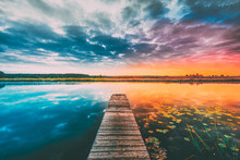 Landscape With Wooden Boards Pier On Calm Water Of Lake, River At Sunset Time, Forest On Other Side. Summer To Autumn Season Transition Concept In Nature
