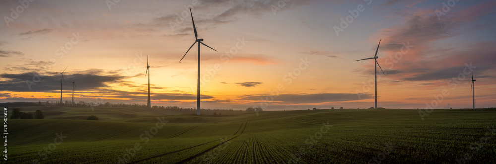 windmills on a field in Germany during a beautiful multicolored sunrise - obrazy, fototapety, plakaty 