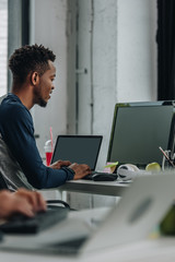 young african american programmer working in office near colleague