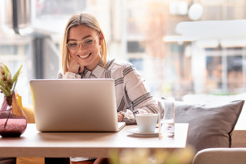 Portrait of young woman using laptop at cafe, she is working on laptop computer at a coffee shop.