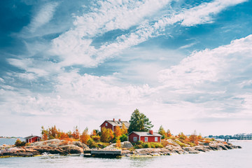 suomi or finland. beautiful red finnish wooden log cabin house on rocky island coast in summer sunny