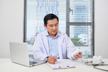 Wall Mural - male doctor holding a box of pills in medical office