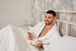 © svetlanaz - Handsome man lying on the bed, happy smile drinking coffee in the morning, attractive guy smiling in the bedroom at home, sexy young male model