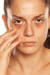 Poster - Young woman touching her low eyelids on yellow background