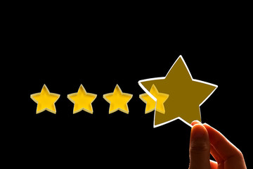 A woman gives a fifth star rating, the concept of a positive rating, reviews and feedback on black background.